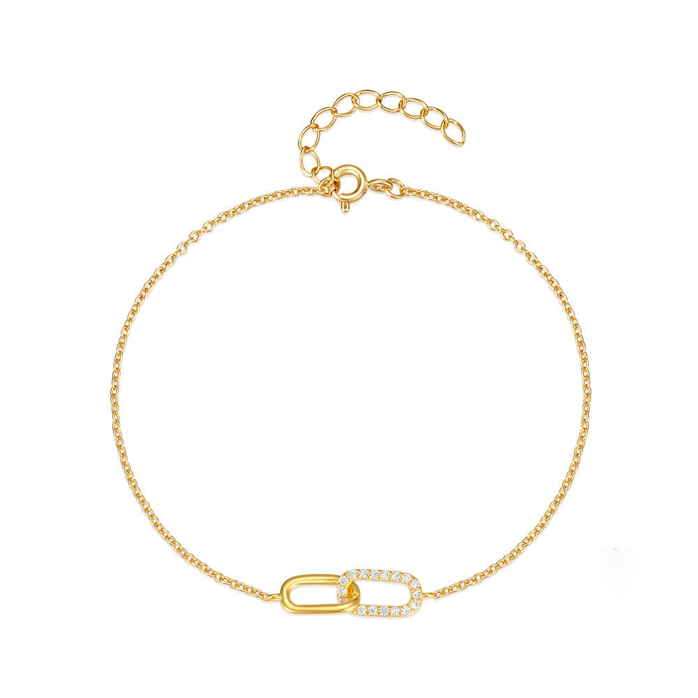 A wrist adorned with a sleek cross-clasp bracelet crafted from polished S925 sterling silver, featuring sparkling cubic zirconia stones embedded in a minimalist dual-buckle design. The bracelet pairs effortlessly with both professional attire and casual outfits, offering a subtle yet refined statement for daily wear.