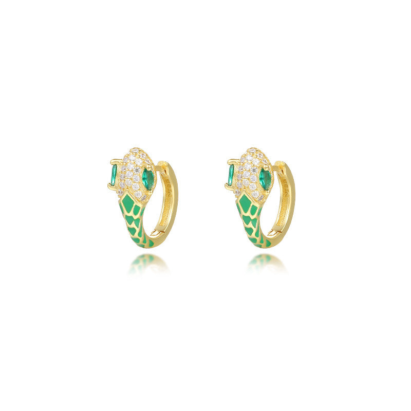 A dynamic close-up of coiled serpent-inspired earrings crafted from S925 sterling silver, adorned with rainbow zirconia stones and glossy resin accents. The hoops elegantly wrap around the earlobe, styled with a monochrome outfit to highlight their eye-catching colors for both day and night occasions.