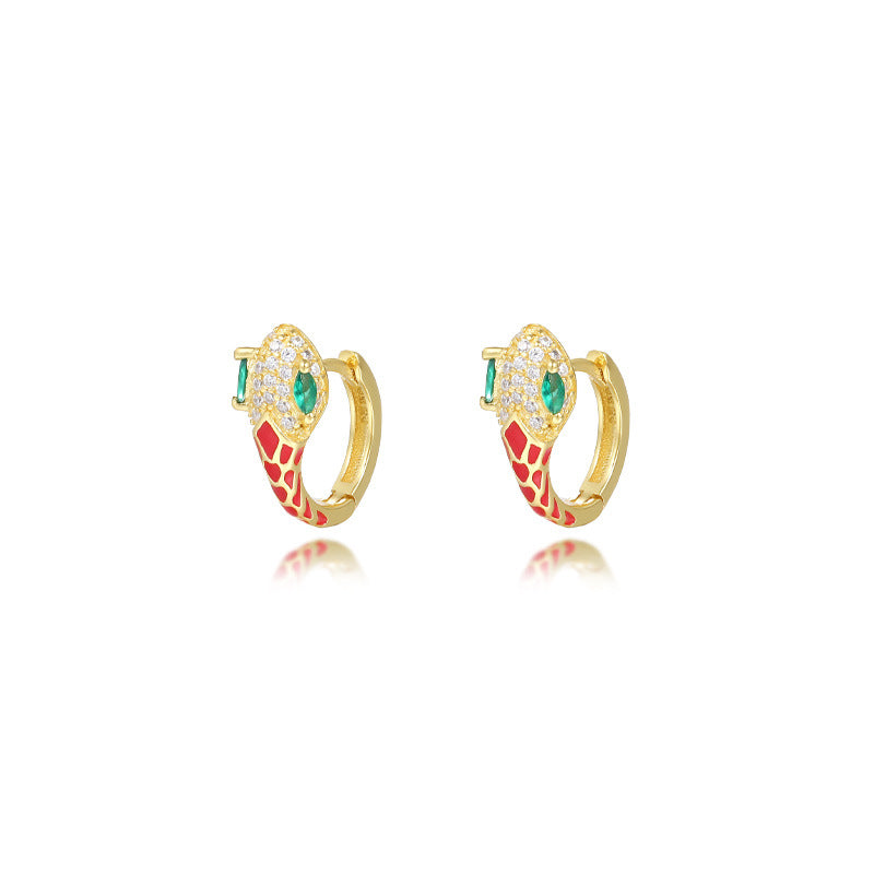 A dynamic close-up of coiled serpent-inspired earrings crafted from S925 sterling silver, adorned with rainbow zirconia stones and glossy resin accents. The hoops elegantly wrap around the earlobe, styled with a monochrome outfit to highlight their eye-catching colors for both day and night occasions.