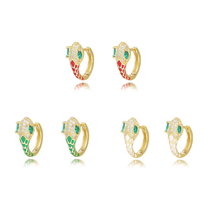 A dynamic close-up of coiled serpent-inspired earrings crafted from S925 sterling silver, adorned with rainbow zirconia stones and glossy resin accents. The hoops elegantly wrap around the earlobe, styled with a monochrome outfit to highlight their eye-catching colors for both day and night occasions.