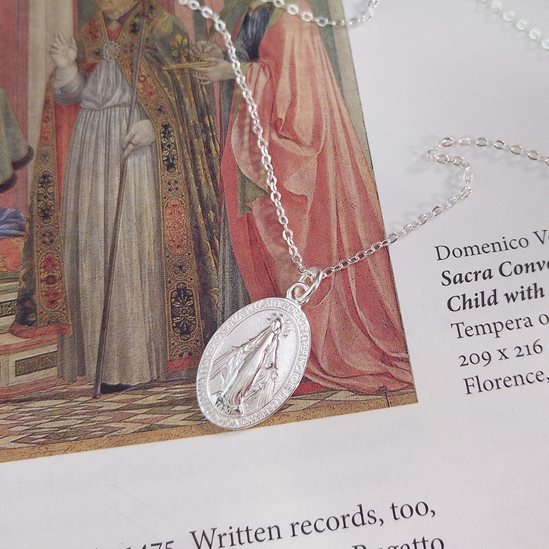 A model wearing a vintage-inspired portrait pendant necklace crafted from 925 sterling silver, featuring a unique round medallion design with intricate details. The necklace is styled with a casual outfit for daily wear or as a meaningful artistic gift, showcasing a polished silver finish.