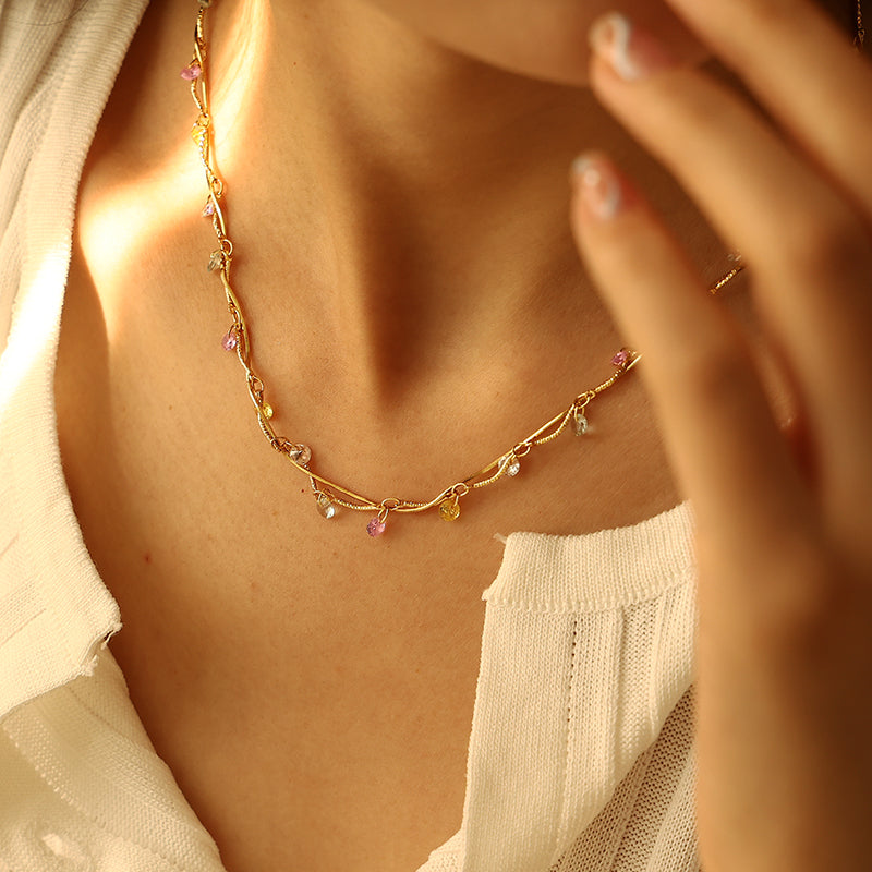 This image displays a luxurious 18K gold-plated brass necklace featuring a spiral design with colorful zircon stones. The necklace has a retro French-inspired style, perfect for casual or semi-formal events. Its vibrant color and elegant design make it a standout accessory for both daytime and evening wear.