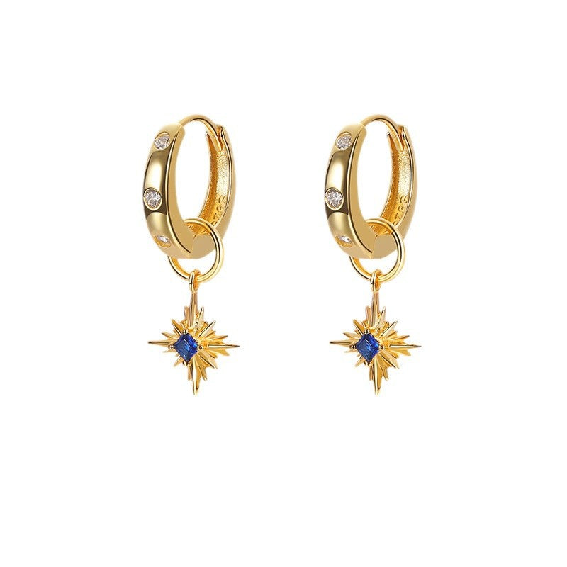A model wearing vintage-inspired blue star dangle earrings made of 925 sterling silver, featuring sparkling sapphire cubic zirconia stones in a winter holiday party outfit. The earrings showcase a silver and icy blue color palette, perfect for retro-style evening events or as a festive gift.